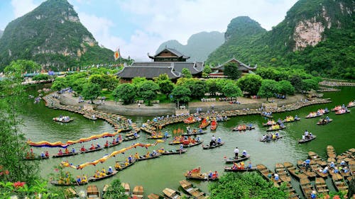 Aerial Photography of Building Surrounded With Body of Water With Boats Across Tree Covered Hills