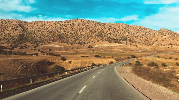 广阔的沙漠景观中，蜿蜒的道路穿过蔚蓝的天空下