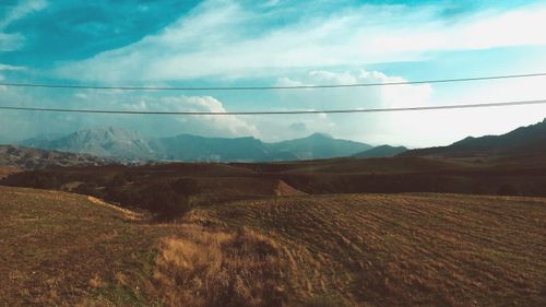 Free Peaceful countryside view with mountains under cloudy sky and cable wires. Stock Photo