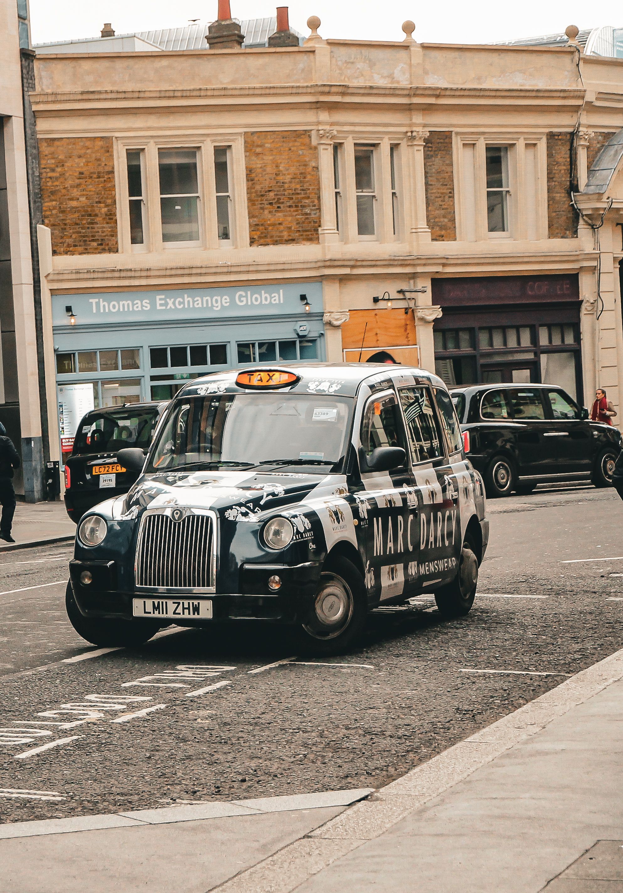 Iconic London black cab driving on city street, capturing urban life and architecture.