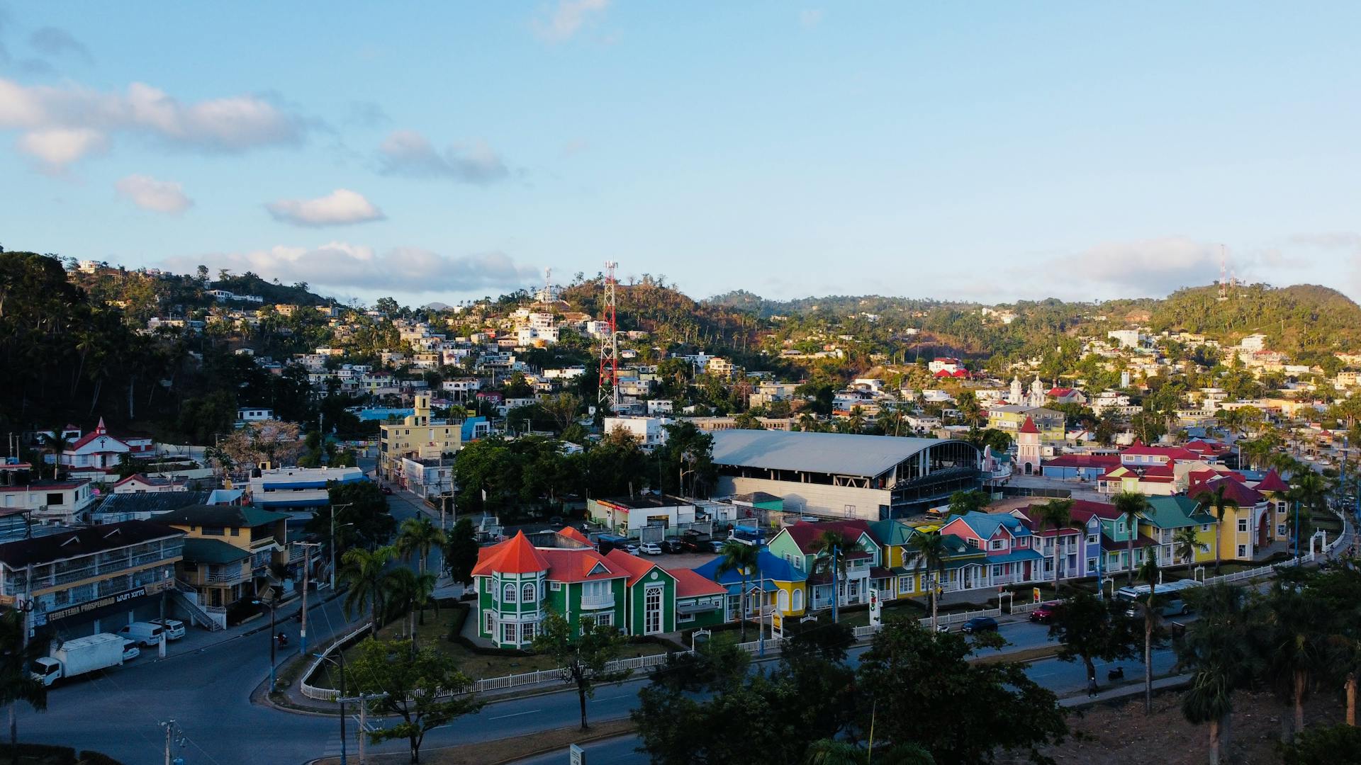 A vibrant aerial view of a colorful town nestled in the Dominican Republic hills.