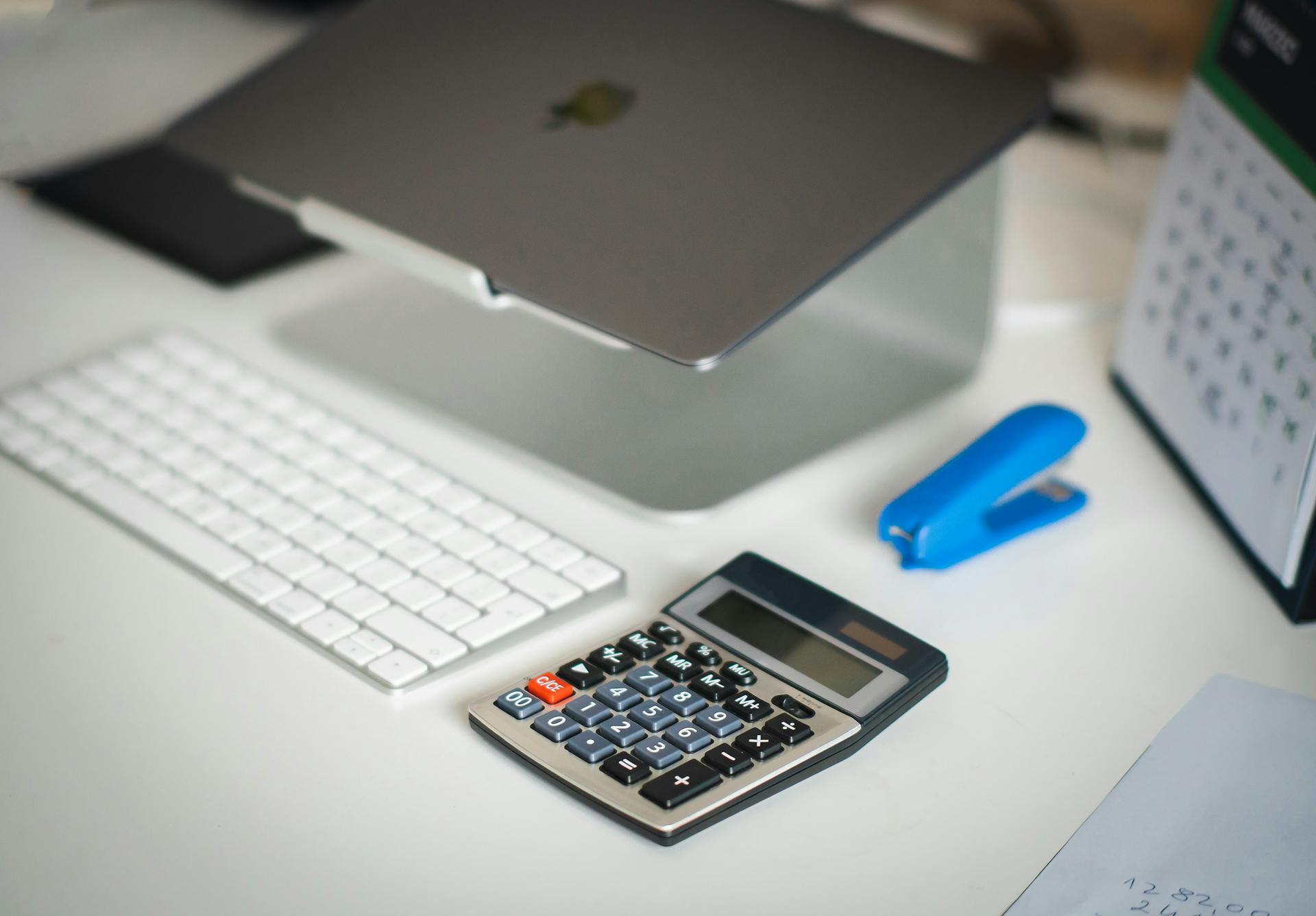 A tidy office desk featuring a laptop, calculator, keyboard, and calendar for business planning.