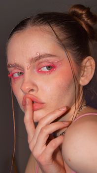 Close-up portrait of a young woman with creative pink makeup and artistic expression.