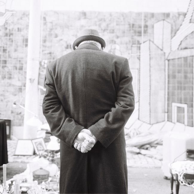 A mysterious man in a long coat at a Lisbon flea market. Black and white photography.
