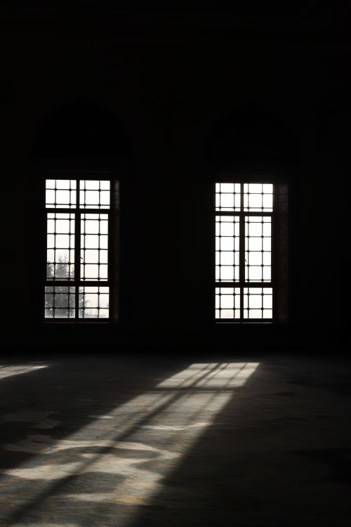 Free Dramatic sunbeams cast through large vintage windows of an empty room. Stock Photo