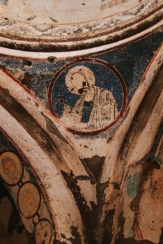 Close-up of a worn religious fresco painting on a historic wall.