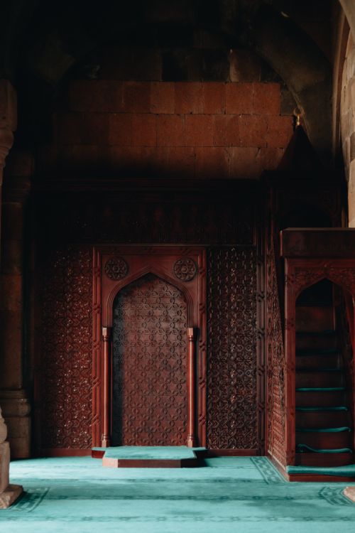 Free Beautiful intricately carved wooden wall in a dimly lit historic mosque interior. Stock Photo