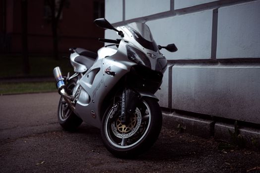 Stylish silver motorcycle parked next to an urban wall, showcasing modern design and power.