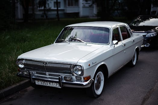 Classic Gaz-24 car with white livery parked on a city street, showcasing vintage style.