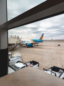 View of a commercial airplane from an airport terminal window on an overcast day.
