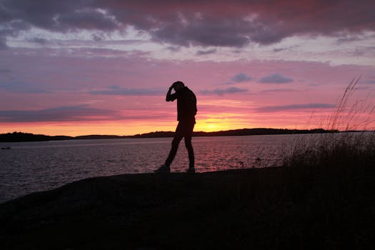 A man walking near water at sunset creates a dramatic silhouette in Stockholm.