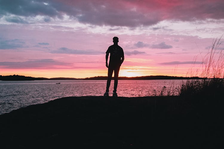 Silhouette Standing On Shore At Amazing Sunset