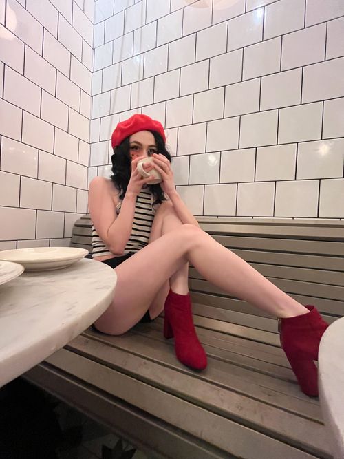 Free Stylish young woman in a Parisian cafe, sipping coffee and wearing a red beret and heels. Stock Photo