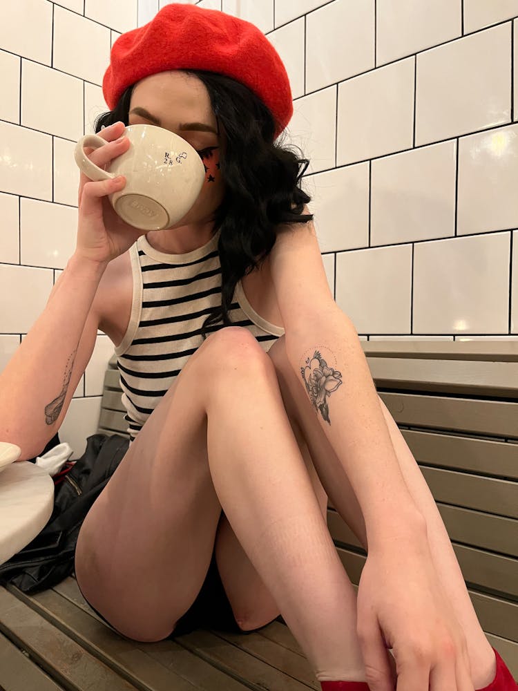 Woman In Beret Sitting And Drinking From Cup