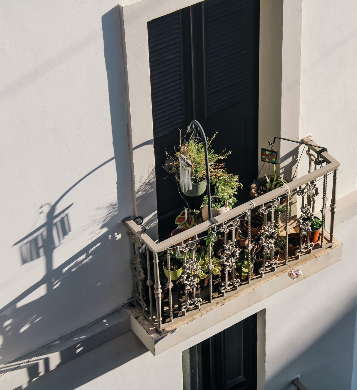 Varanda de apartamento ensolarada com vasos de plantas e jardim pequeno