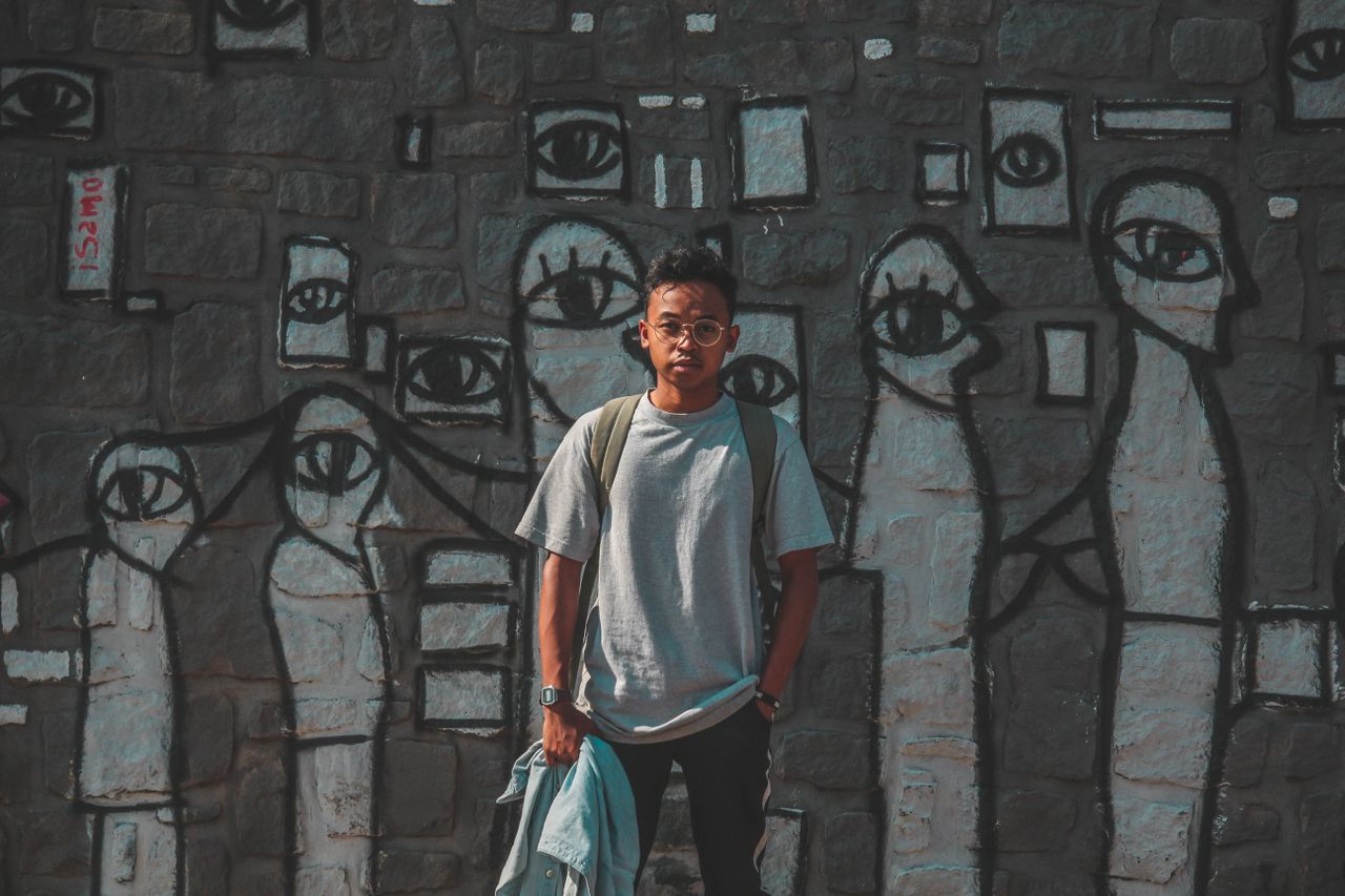 a young man stands confidently before a vibrant graffiti mural capture
