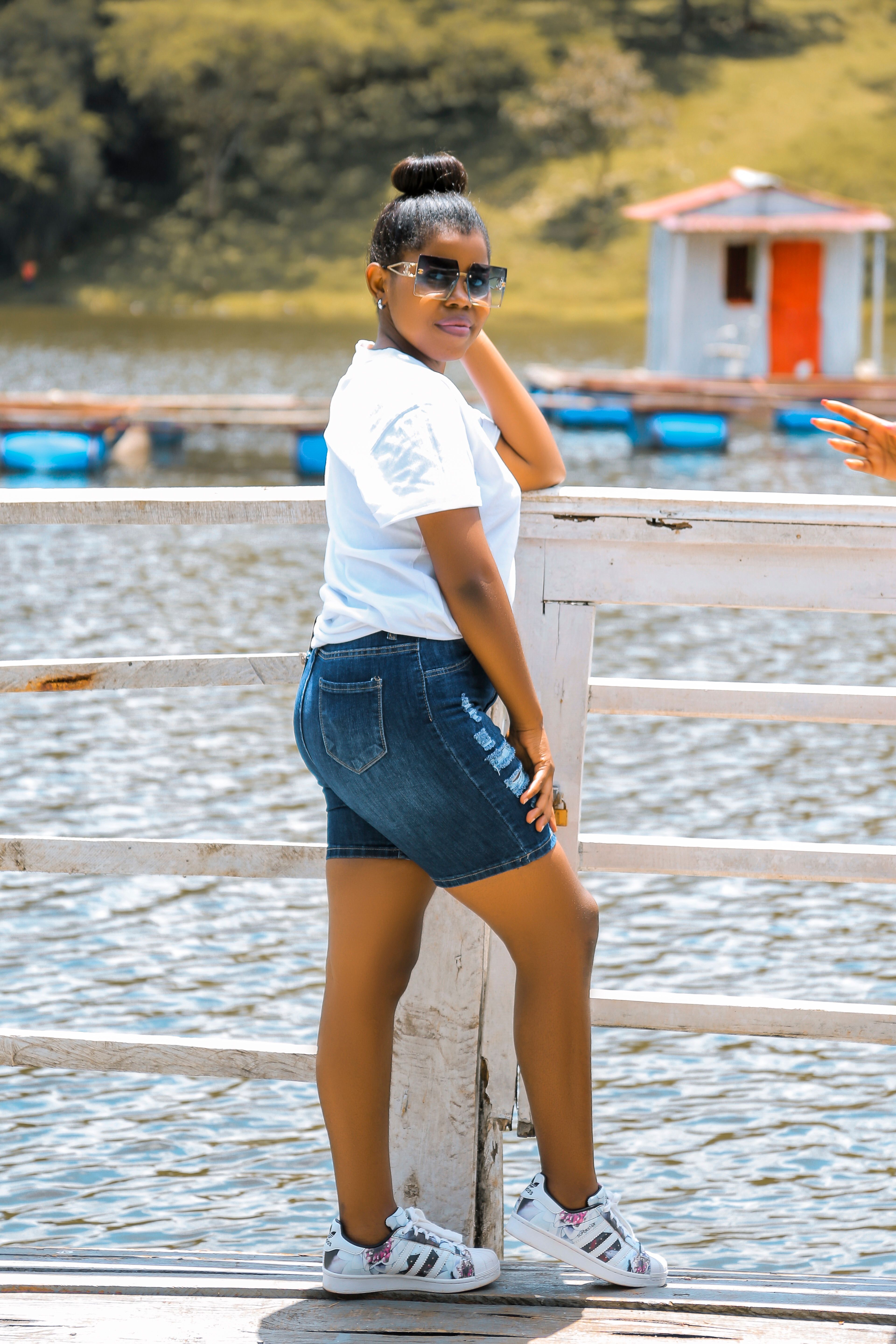 Young woman in denim shorts and sunglasses enjoying a summer day by the water.