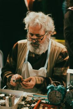 Senior artisan repairing clocks with tools, showcasing craftsmanship and precision. - Fotografer Sidoarjo