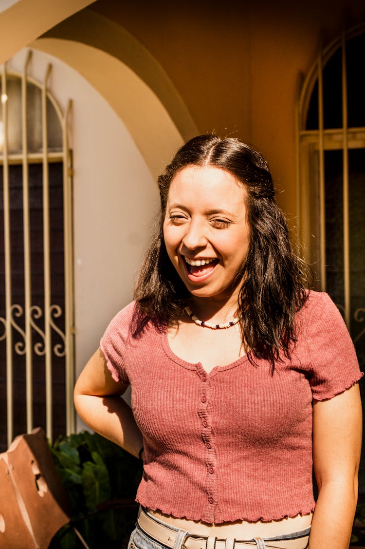 Young Woman Standing Outside In Sunlight And Smiling