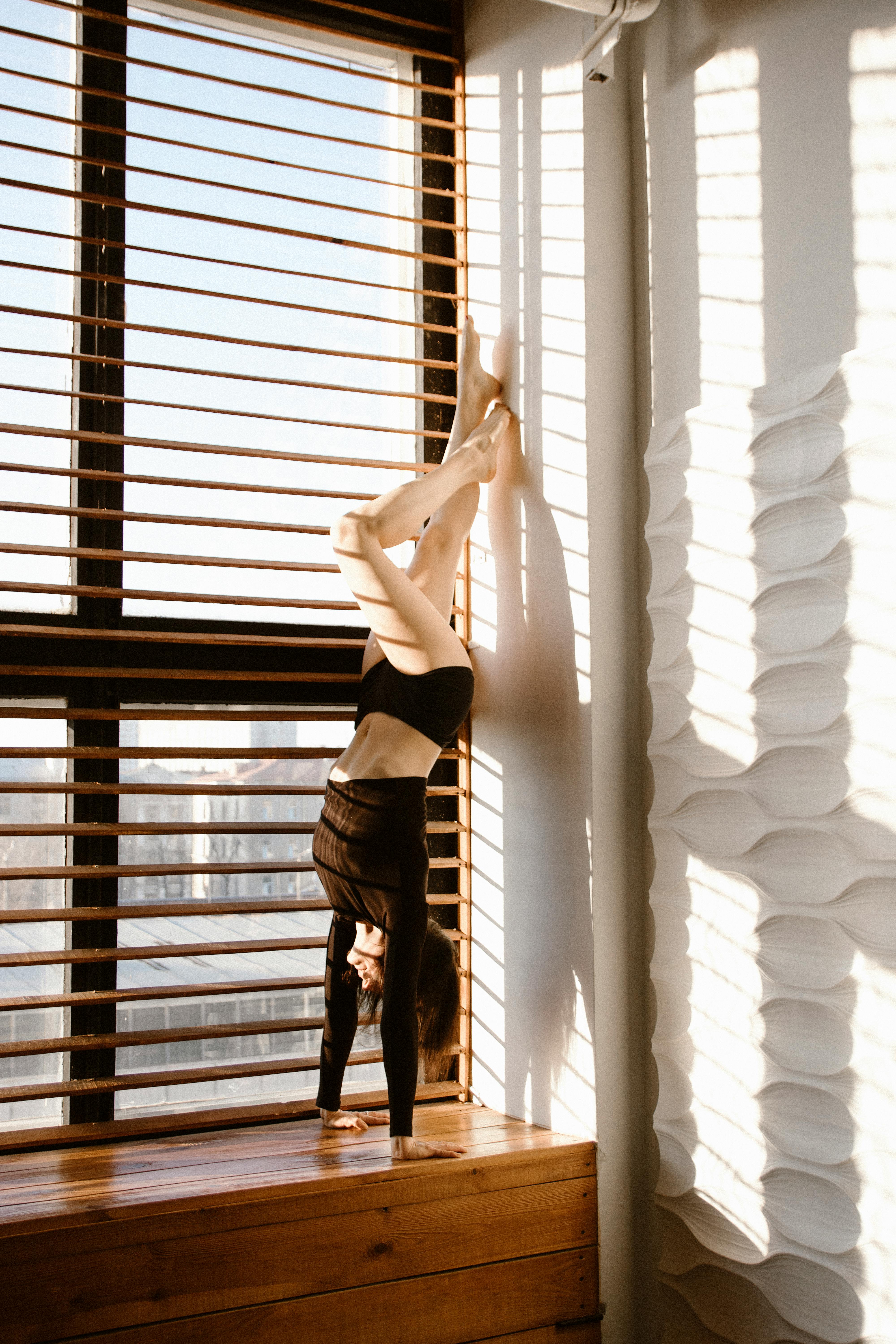 woman standing on hands near window