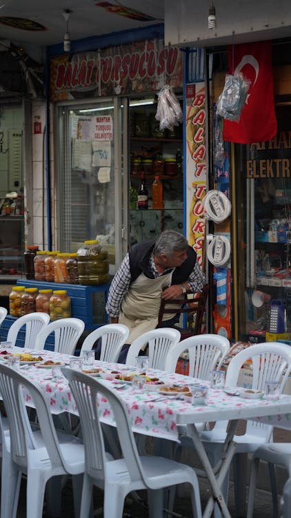 Man Standing in front of a Restaurant with a Set Table Standing Outside 