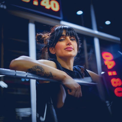 A woman with tattoos on her arm is sitting on a bench