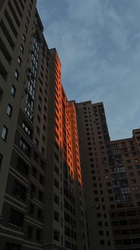 Tall apartment blocks with a warm sunset reflection under a cloudy sky.