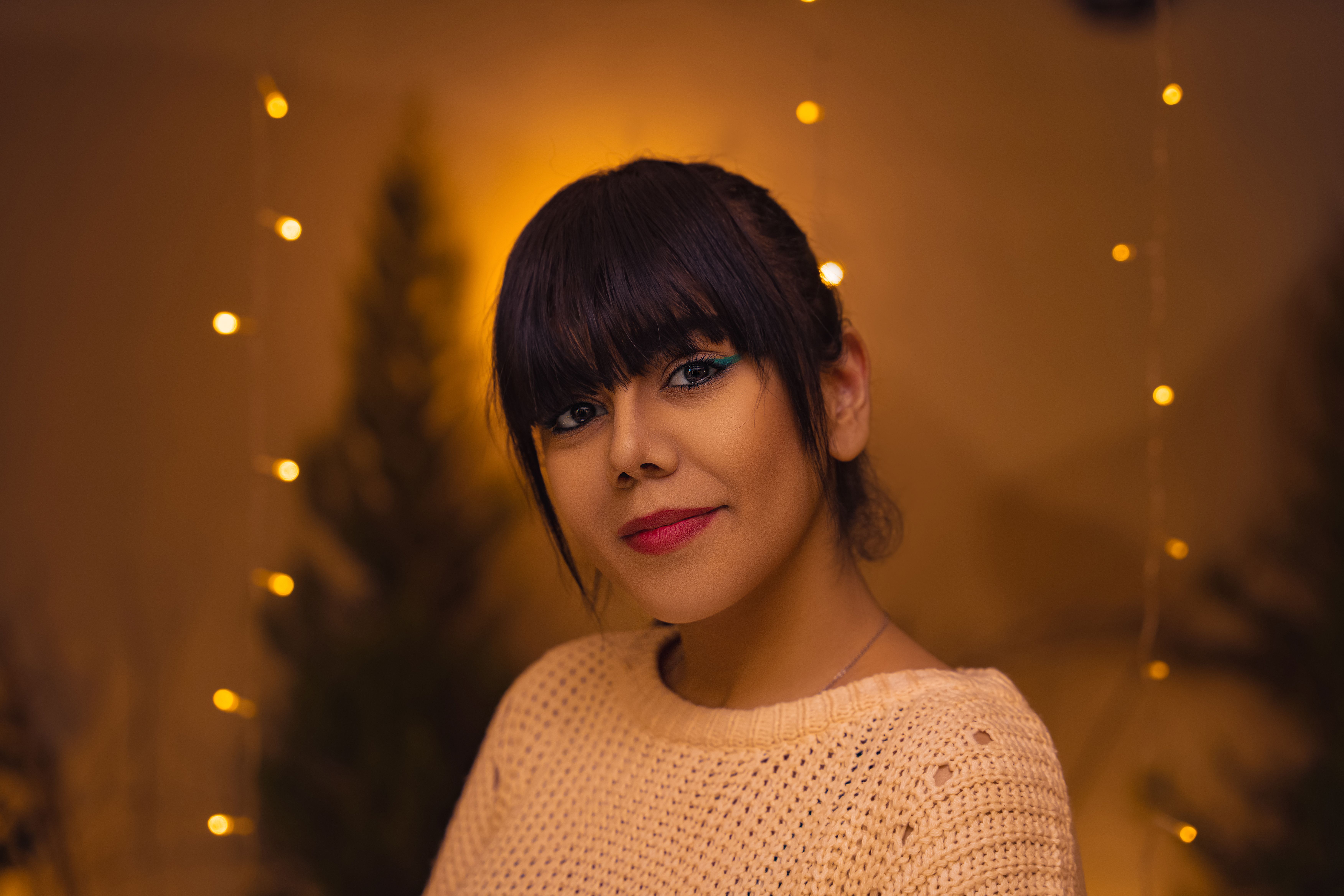 A person in comfortable loungewear smiling while walking on a walking pad, with fairy lights in the background