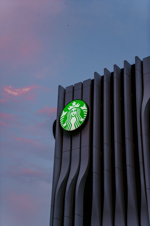 Free A low angle view of a modern building with a Starbucks logo against a vibrant sky in Panama City. Stock Photo
