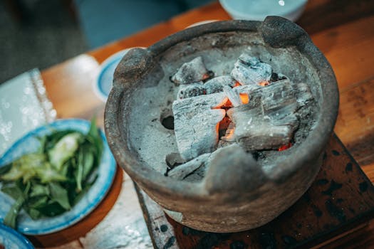 A rustic clay pot filled with glowing embers on a wooden table, perfect for rustic cooking themes.