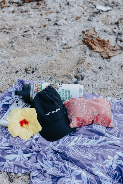 Hibiscus Flower Lying next to Water Bottle on Blanket on Sand