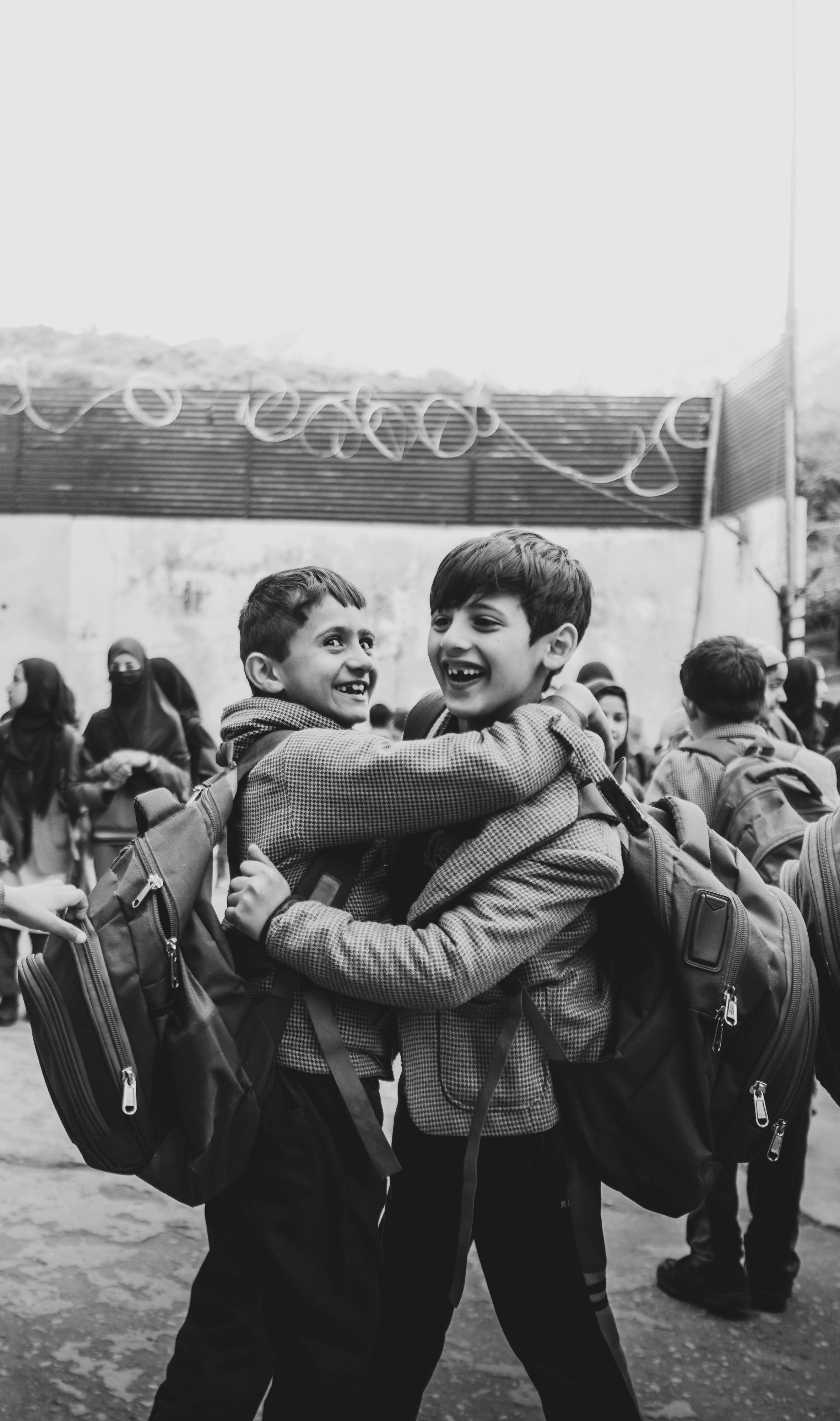 Two boys sharing a joyful embrace at school, symbolizing friendship and happiness.
