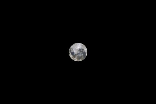 Free A crisp image of the full moon centered against a dark, clear night sky. Stock Photo