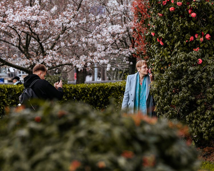 Man Photographing Woman Smelling Flower In Park