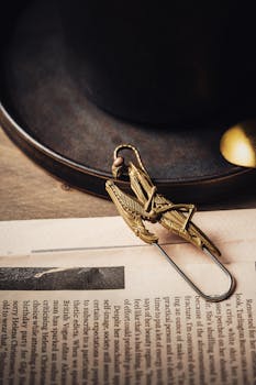 Close-up of a brass praying mantis-shaped clip resting on a newspaper, symbolizing elegance and functionality.