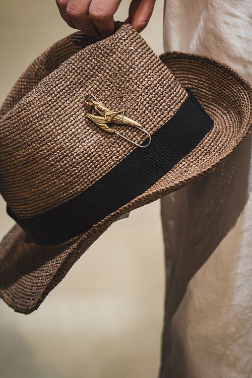 Free Elegant straw hat adorned with a grasshopper brooch, showcasing unique fashion style. Stock Photo