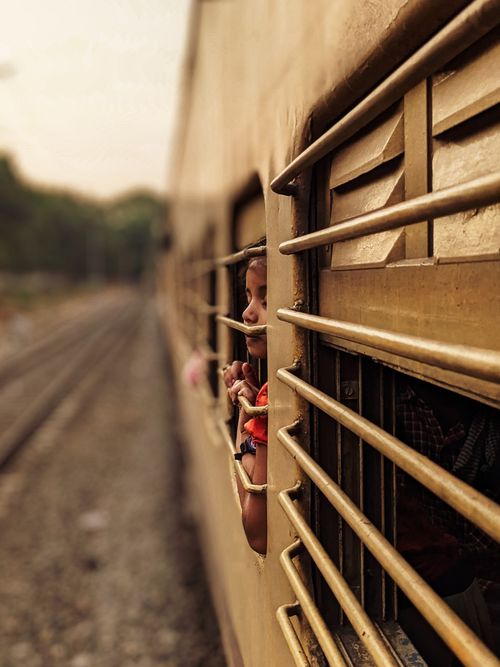 Free A child peeks out of a train window, embracing the excitement of travel. Candid and evocative. Stock Photo