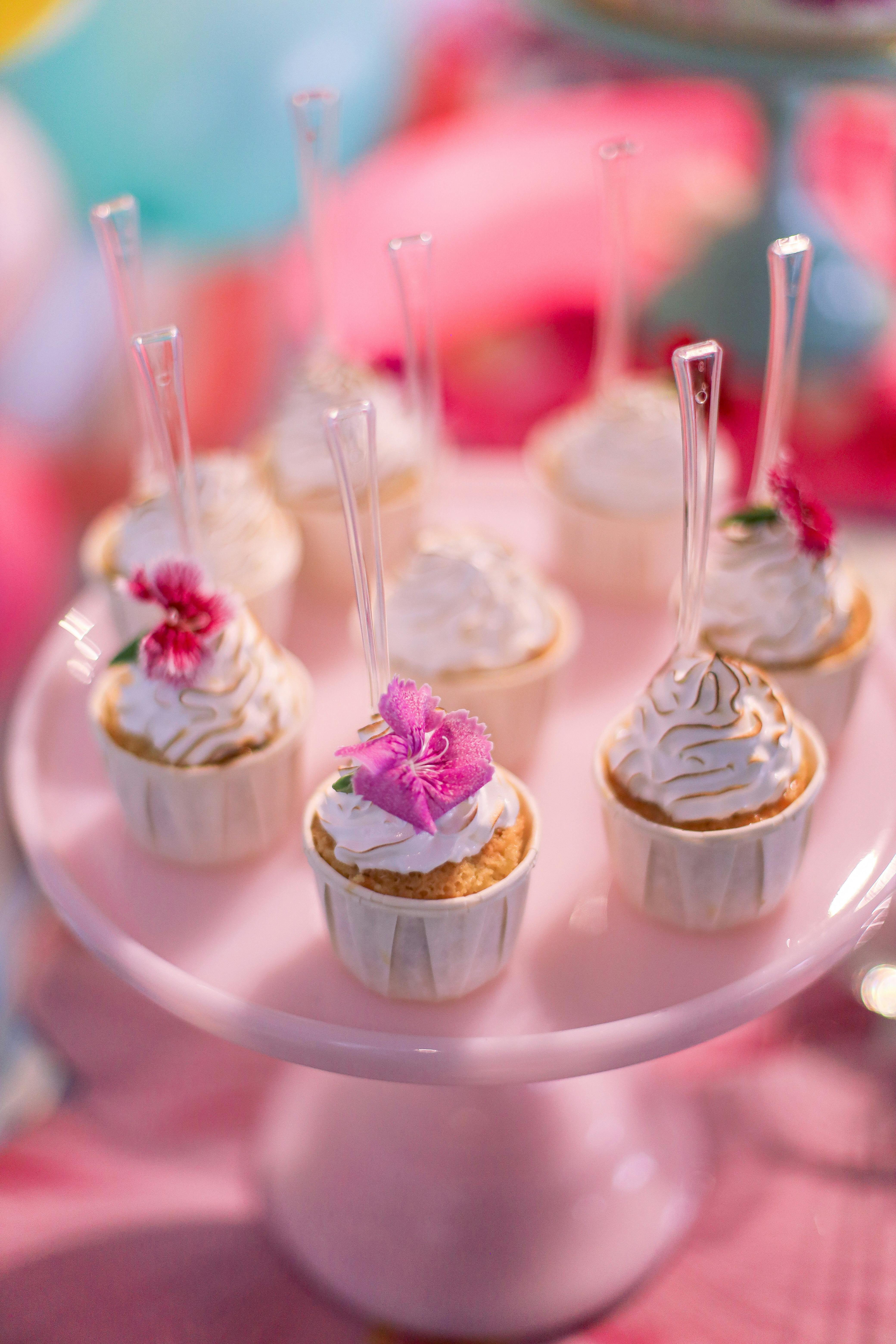 Elegant floral-topped cupcakes on a pink stand, perfect for parties and celebrations.