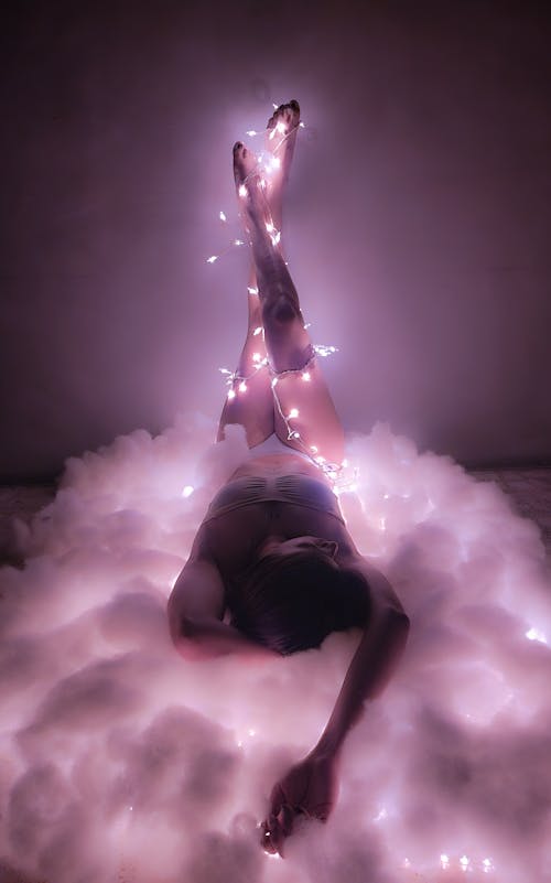 Woman in Lingerie with Lamps on Her Body Lying on Cloud