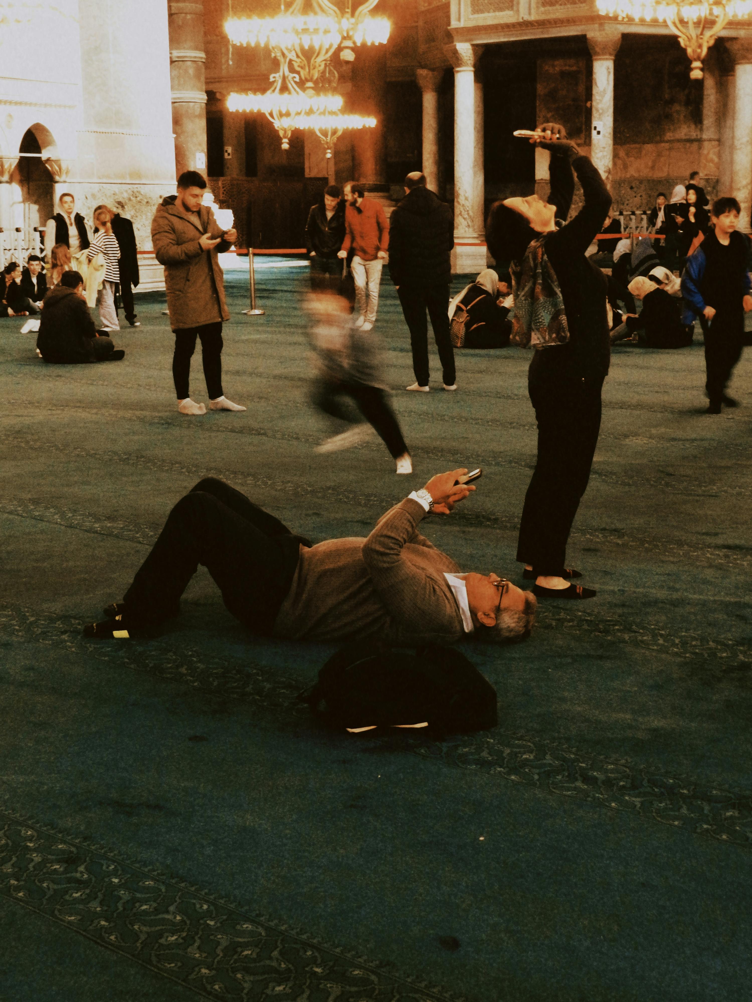 Visitors using smartphones to photograph the stunning architecture inside a grand mosque.