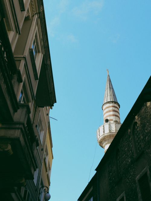 Free Photo of a minaret rising between urban architecture under a clear blue sky. Stock Photo