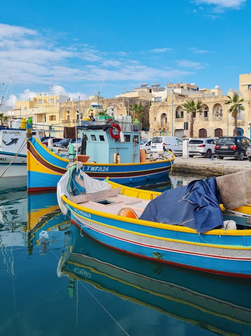 Boat and Motorboat on Sea Shore in Town