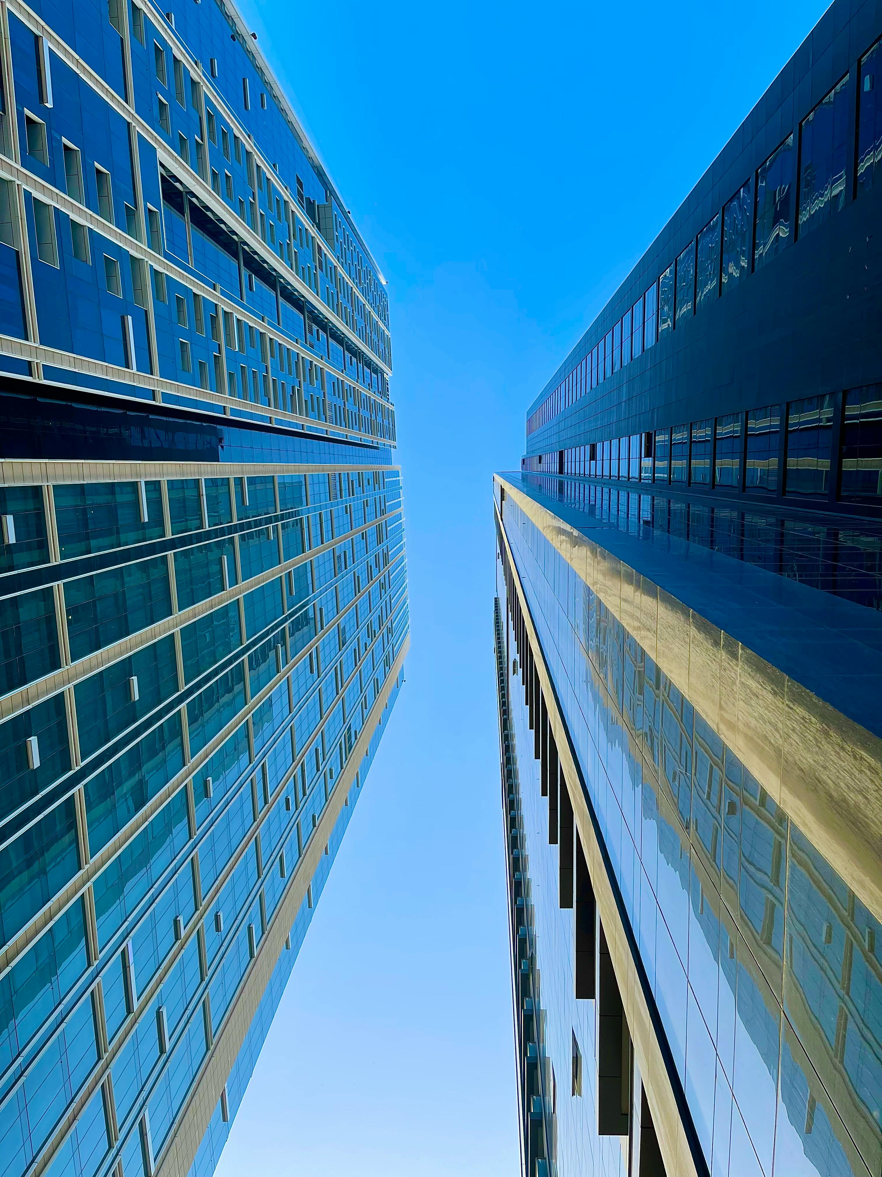Upward view showcasing the sleek architecture of Dubai's modern skyscrapers against a clear blue sky.