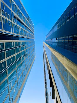 Upward view showcasing the sleek architecture of Dubai's modern skyscrapers against a clear blue sky.