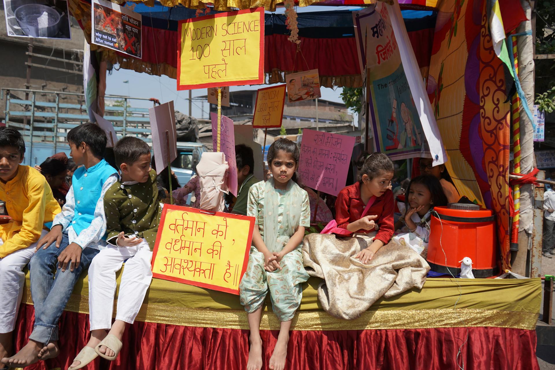 Children adorned in traditional attire sit on a colorful Indian parade float.