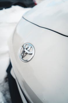 Close-up shot of a white Toyota car hood featuring the logo prominently.