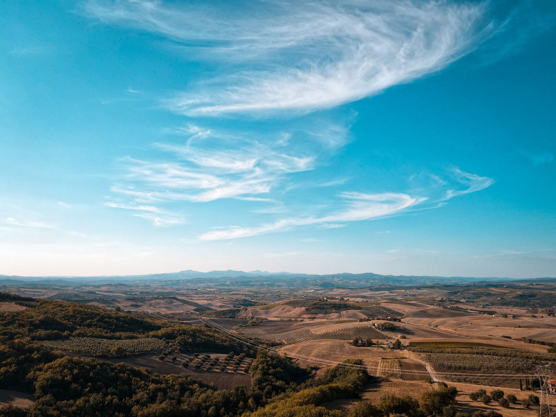 A breathtaking view of rural farmland with rolling hills under a bright blue sky.