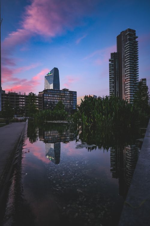 Free Contemporary urban skyline with skyscraper reflections in water at sunset. Stock Photo