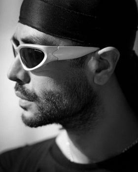 Black and white portrait of a man wearing stylish sunglasses and a bandana.