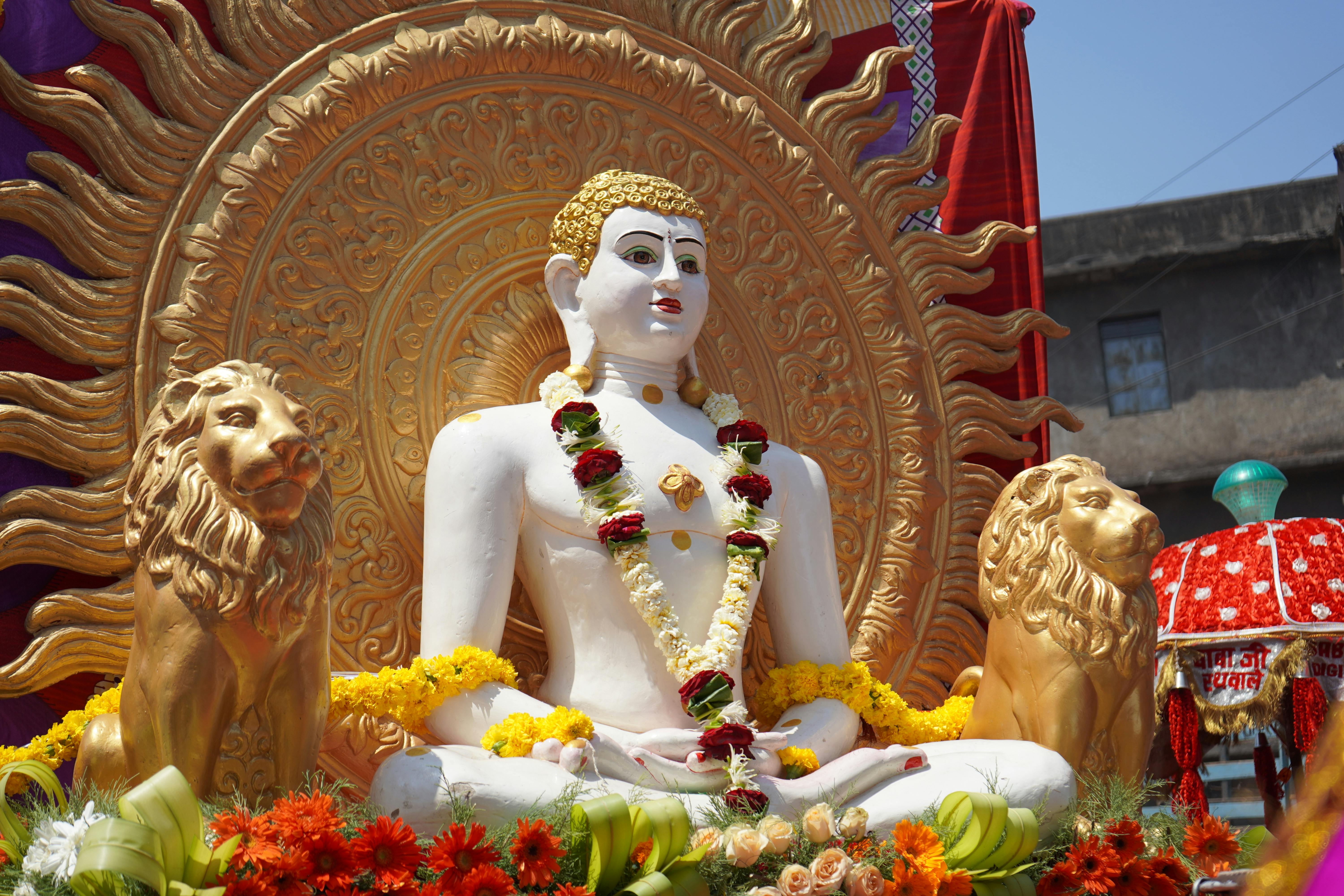 a statue of a buddha in a garden with flowers